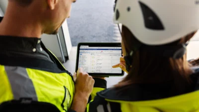 Två byggarbetare tittar tillsammans på en surfplatta som visar kalkylprogrammet Wikells Sektionsdata.