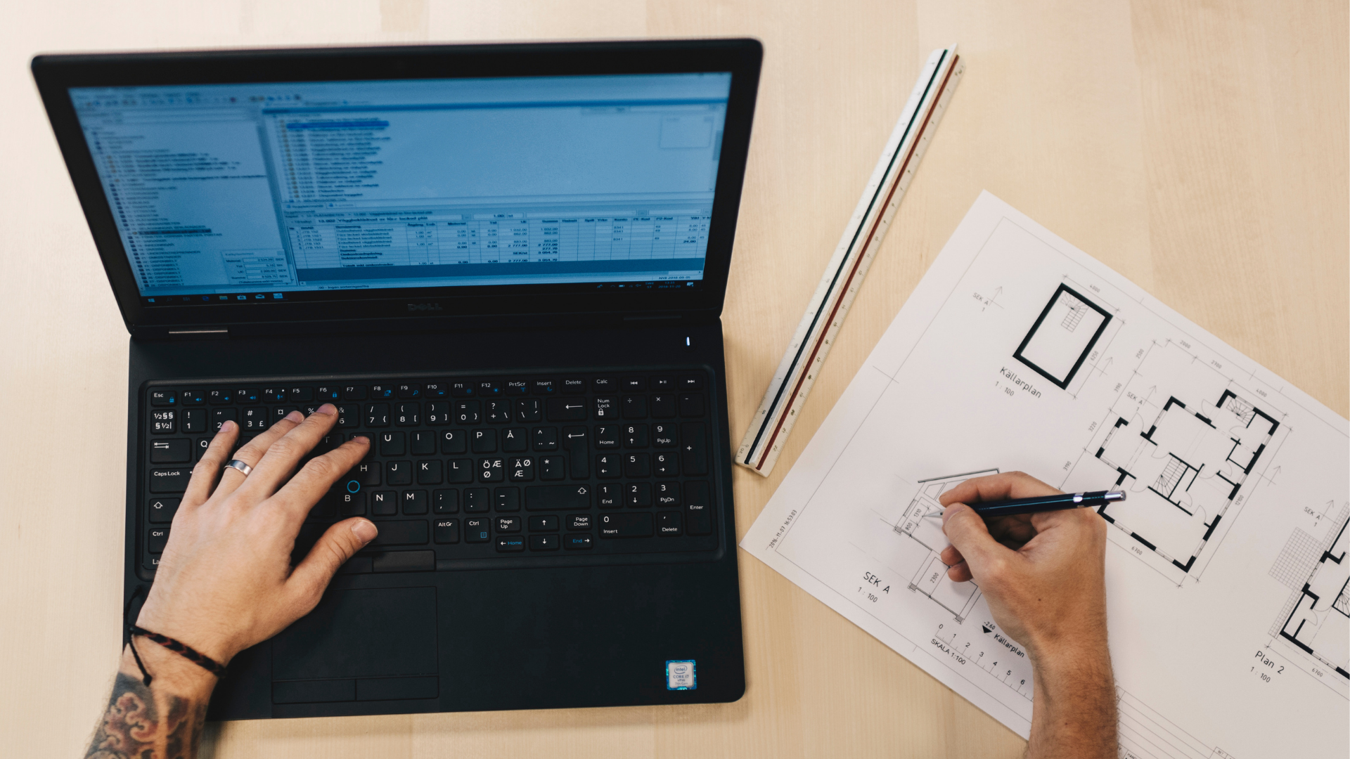 Person arbetar vid laptop samtidigt som en planritning granskas och justeras.